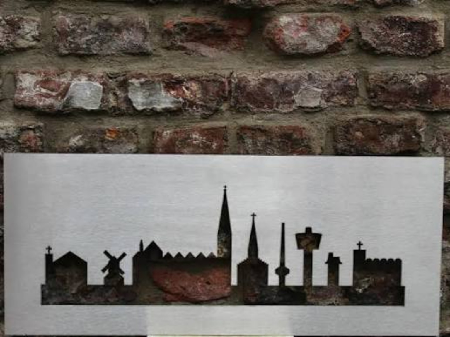 Die Skyline der Dülkener Wahrzeichen als Metallarbeit vor einer Backsteinwand